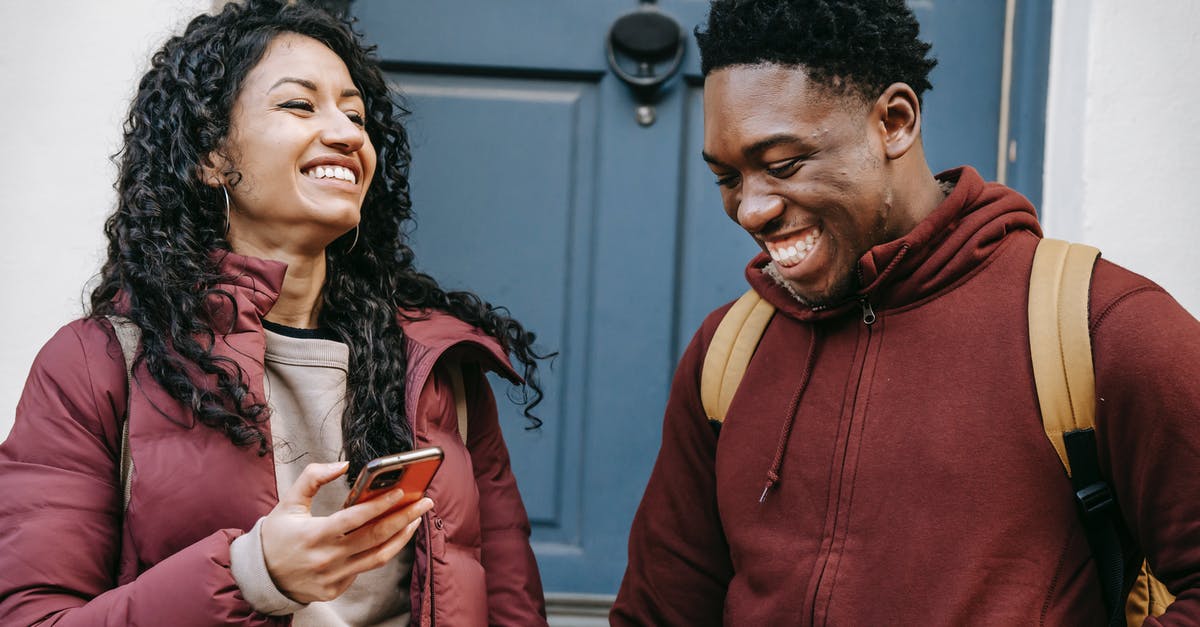 Which entrance to use for the Louvre? - Diverse cheerful friends with smartphone laughing near door of building Which entrance to use for the Louvre? - Diverse cheerful friends with smartphone laughing near door of building
