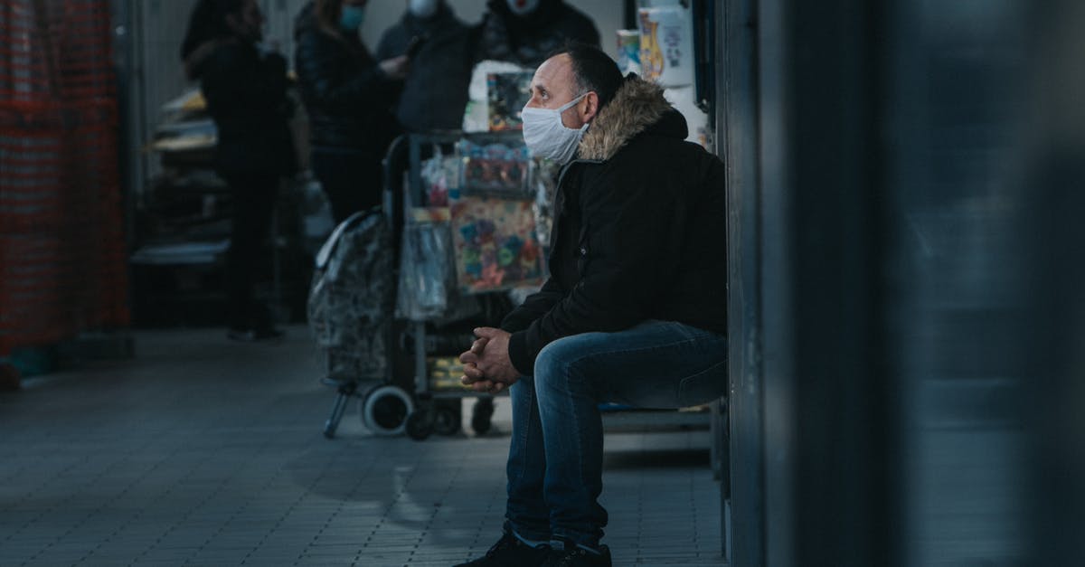 Which forms of luggage protection don't TSA and airline ticketing agents find objectionable? [closed] - Side view of male in warm clothes and mask sitting in public place