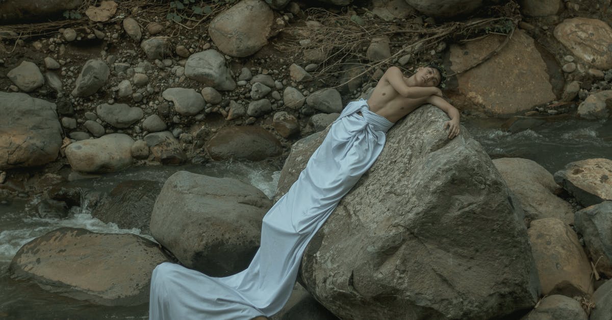 Which Greek islande of the Cyclades is the most wild, or the most quiet? [closed] - Male in long white sheet resting on heavy rough stone near splashing stream
