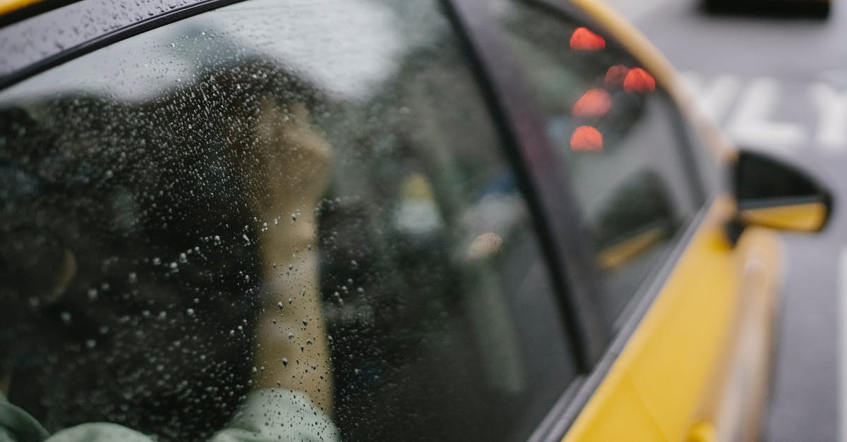 Which parts of Highway 1 are closed at the moment and how to drive around them? - Crop anonymous passenger sitting in yellow taxi car on road in town in rainy weather