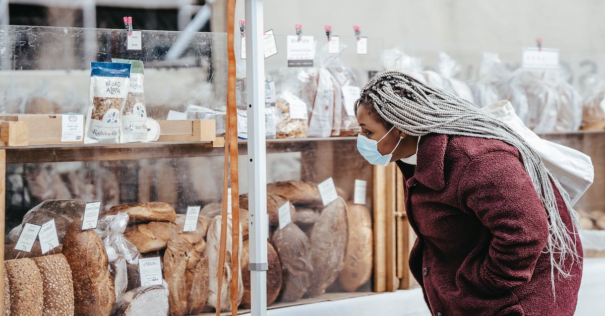 Which website to use when choosing local US flights? - Side view of adult black lady wearing protective mask and warm coat selecting baking goods while standing in street market in daytime Which website to use when choosing local US flights? - Side view of adult black lady wearing protective mask and warm coat selecting baking goods while standing in street market in daytime