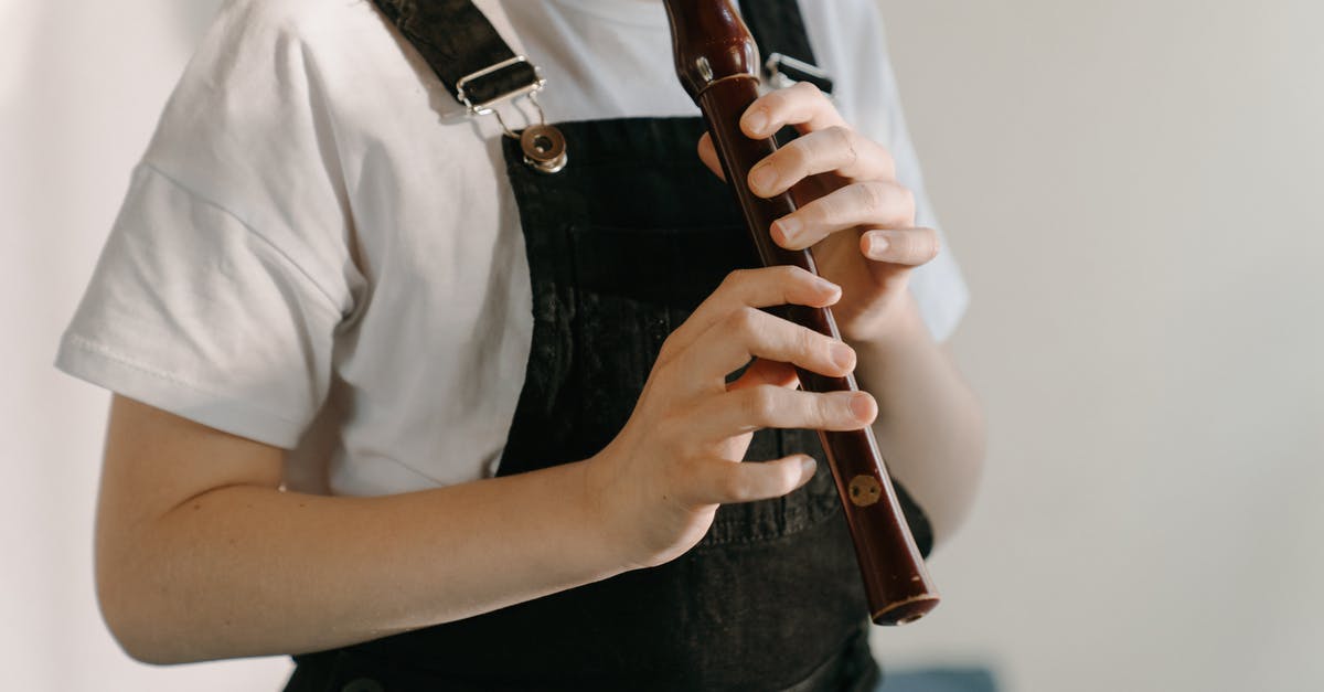 Who is performing the music played on the loudspeakers at Santuario del Cerro San Cristobal, Santiago, Chile? - Person in White Button Up Shirt and Black Denim Jeans Holding Brown Wooden Flute