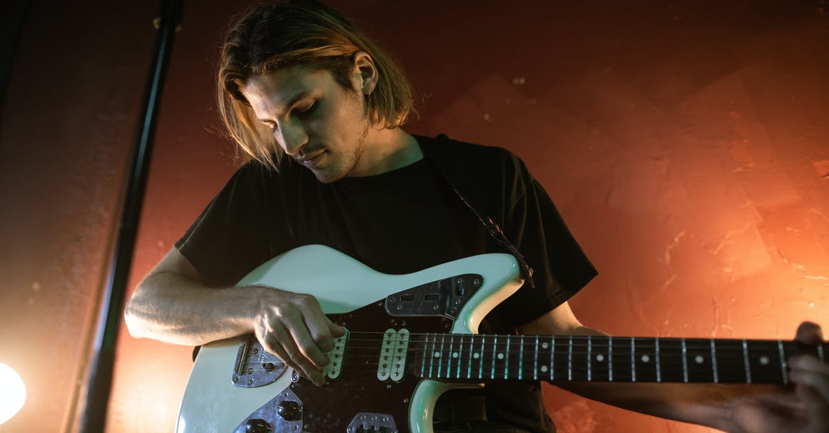 Who is performing the music played on the loudspeakers at Santuario del Cerro San Cristobal, Santiago, Chile? - A Man Playing an Electric Guitar while Sitting