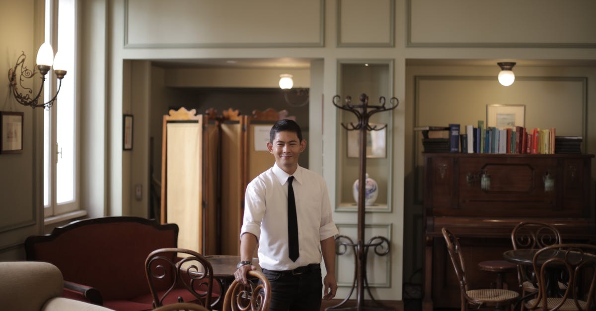 Why do hotels (apparently) require you to leave and then ask for your room key back at the reception when leaving/returning to the hotel? [duplicate] - Cheerful restaurant manager looking at camera