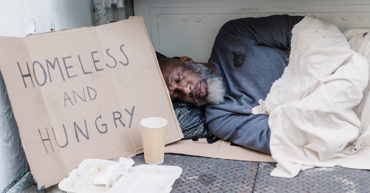 Why do I see so few homeless people / beggars in cities in the Netherlands? [closed] - Photo of a Homeless Man Sleeping Near a Cardboard Sign