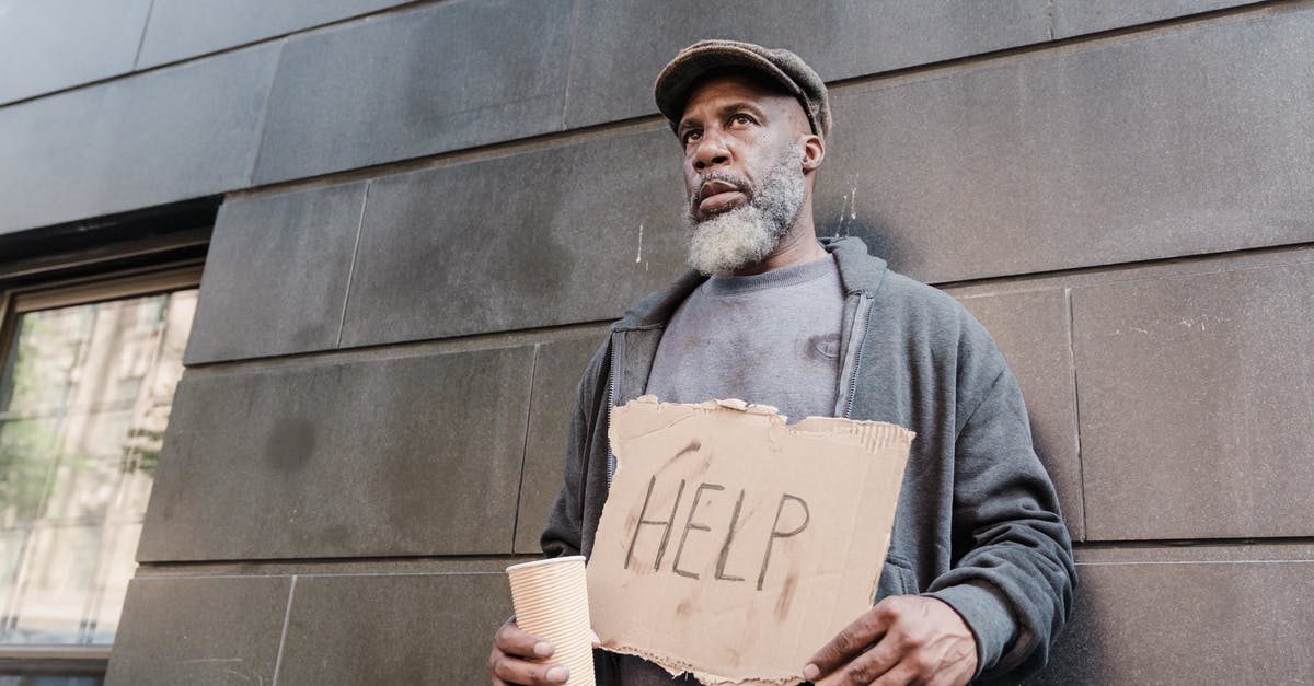 Why do I see so few homeless people / beggars in cities in the Netherlands? [closed] - Low-Angle Shot of a Beggar Holding a Cardboard Sign with the Word Help