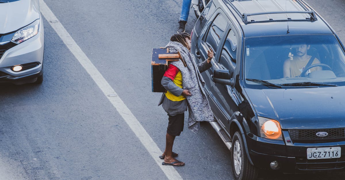 Why do I see so few homeless people / beggars in cities in the Netherlands? [closed] - Man in Blue Denim Jeans Standing Beside Black Suv