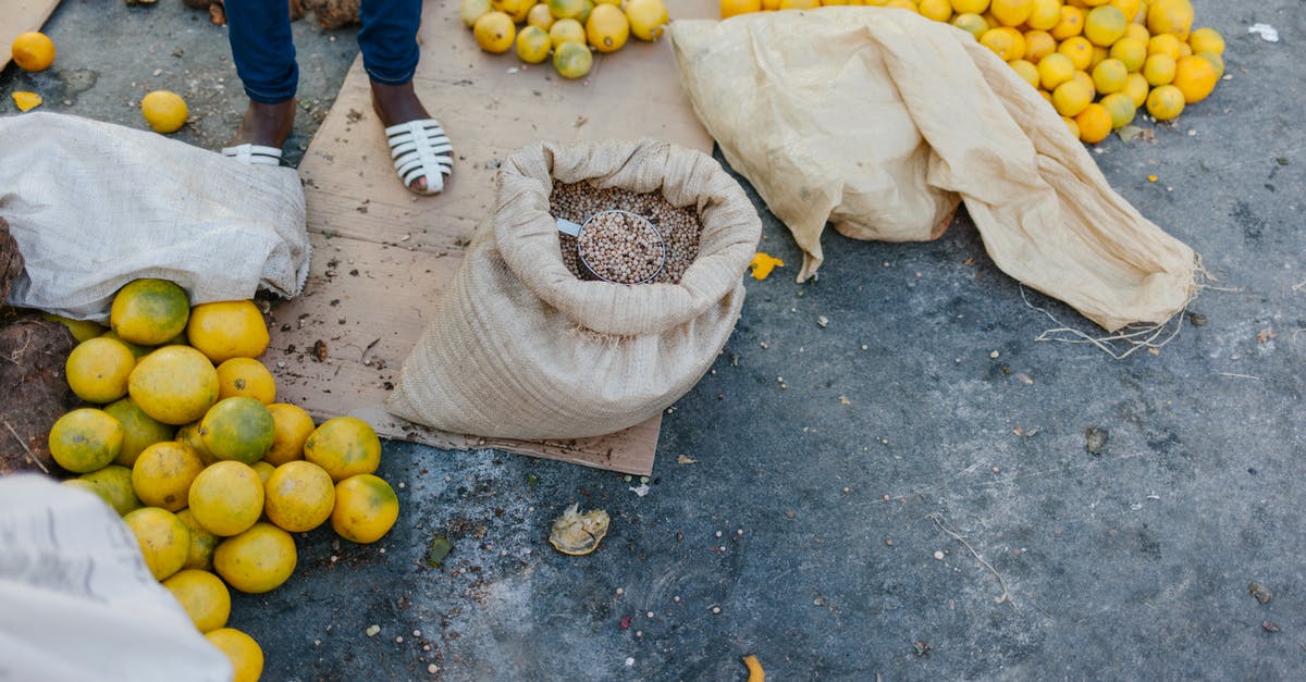 Why do many airports offer bag wrapping services? - From above of crop faceless seller near pile of ripe oranges on ground and bag of grains at bazaar Why do many airports offer bag wrapping services? - From above of crop faceless seller near pile of ripe oranges on ground and bag of grains at bazaar
