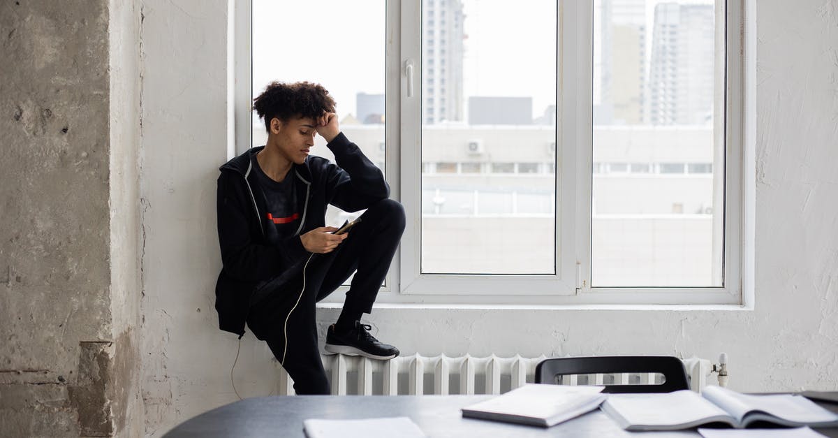Why do some airlines charge more for break journeys - Tired African American male student surfing charging mobile phone during break in studies in loft style room Why do some airlines charge more for break journeys - Tired African American male student surfing charging mobile phone during break in studies in loft style room