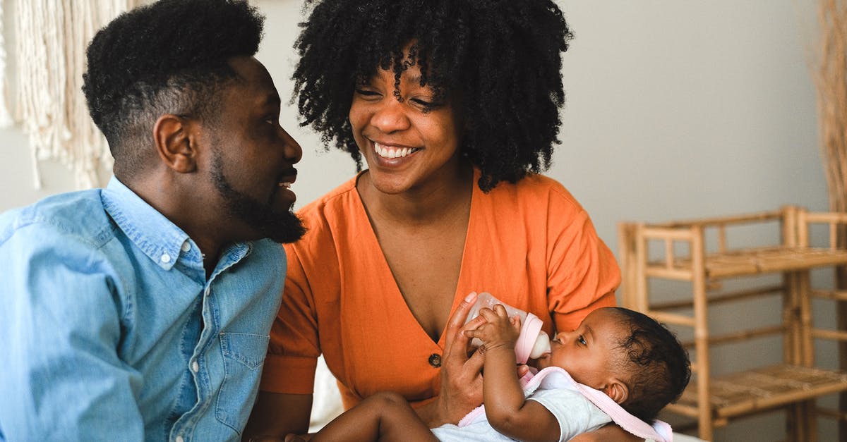 Why do some groups of tourists include someone carrying a banner? - Happy Couple Sitting on Bed Carrying a Baby Why do some groups of tourists include someone carrying a banner? - Happy Couple Sitting on Bed Carrying a Baby