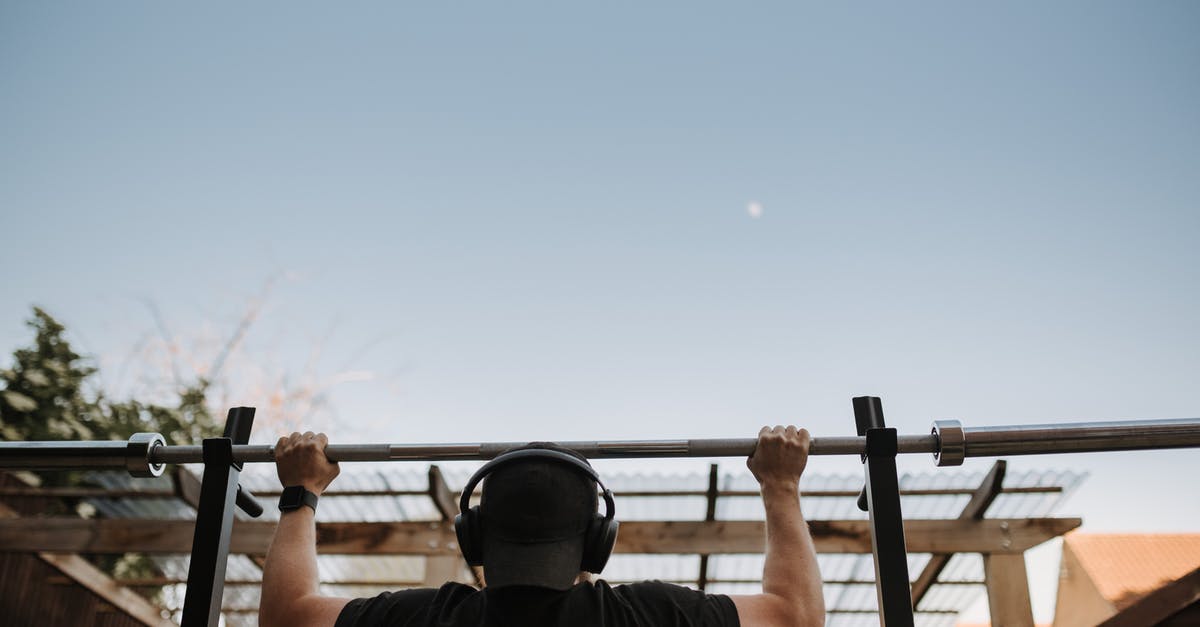 Why does the Shanghai Maglev train cabin have a power bar and a portable fan? [closed] - Back view of anonymous muscular male athlete listening to music in headphones while exercising on bar under light sky