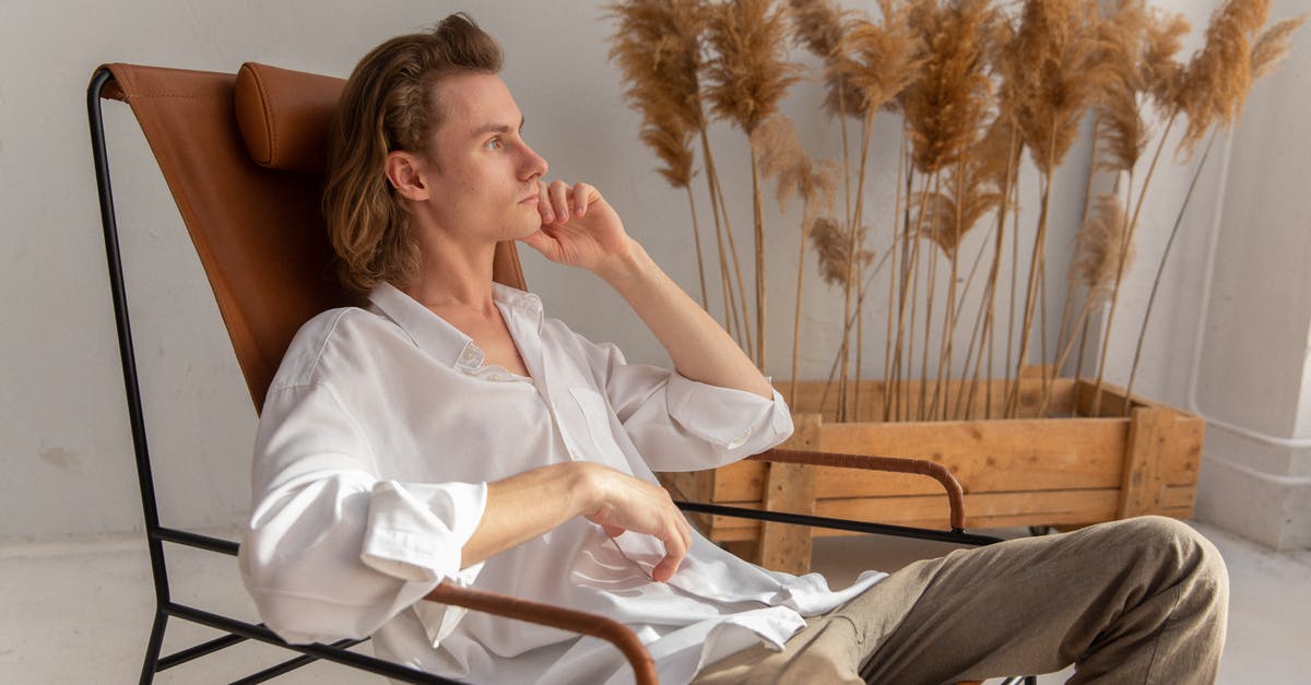 Why does the window-side armrest never move? - Side view of pensive male in white shirt sitting on comfortable armchair with hand at chin and looking in distance in room with dried plants Why does the window-side armrest never move? - Side view of pensive male in white shirt sitting on comfortable armchair with hand at chin and looking in distance in room with dried plants