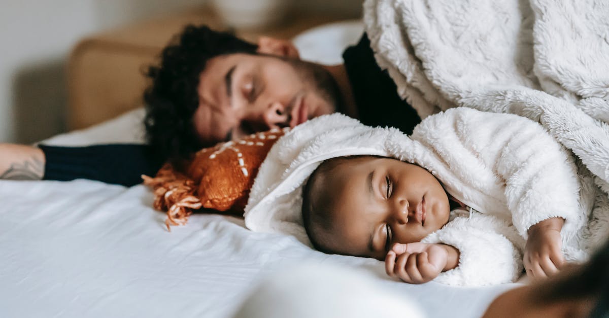 Why is just my wife had been bitten by bed bugs? [closed] - Multiethnic father and newborn baby lying and sleeping together on comfortable bed near crop unrecognizable woman in daylight