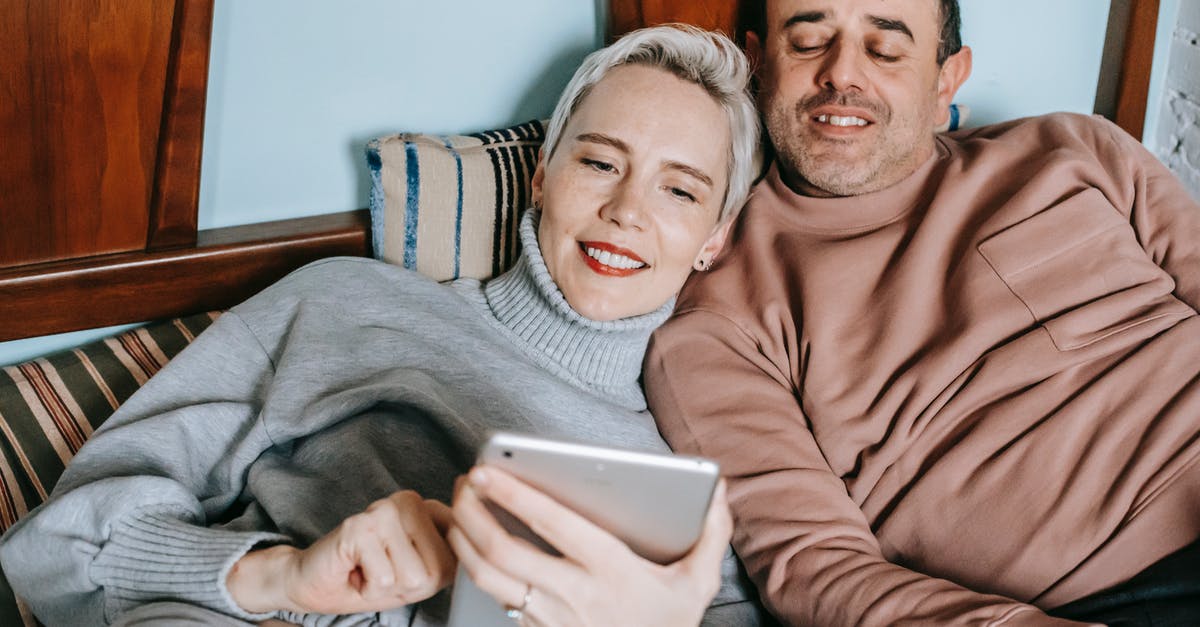 Why is just my wife had been bitten by bed bugs? [closed] - Content diverse middle aged married couple in warm casual clothes lying together on bed and smiling while watching movie on tablet