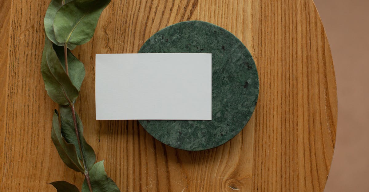 Will airlines let me board with a green card only? - Top view of white mock up business card on round board placed on wooden table with green branch in room Will airlines let me board with a green card only? - Top view of white mock up business card on round board placed on wooden table with green branch in room