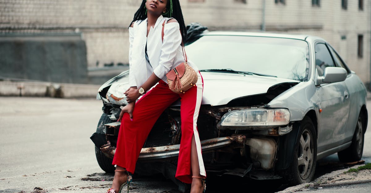 Will an externally damaged passport pose a problem when applying for UK visa? - Woman in White Open Cardigan and Red and White Pants Sitting on Damage White Car