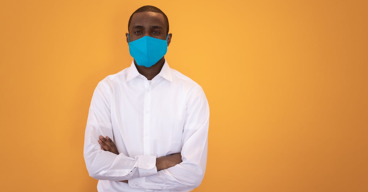 Will an externally damaged passport pose a problem when applying for UK visa? - Black man in mask standing with arms folded in studio