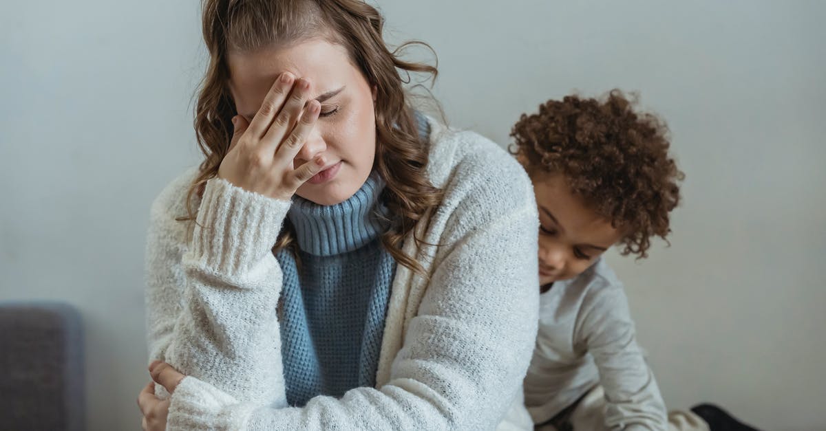 Will bringing my mother in visitor visa to Germany cause any problems when I try to bring prove her hardship? [closed] - Frustrated mother with hand on forehead and closed eyes sitting near African American son near wall in room at home