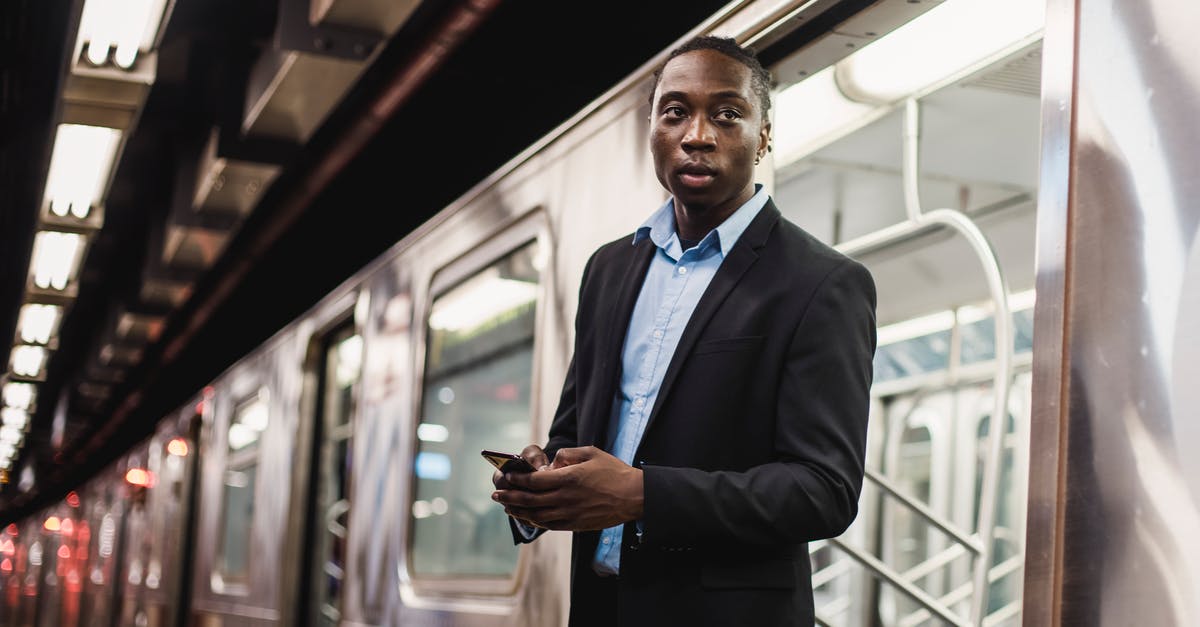 Will I get refund if train was cancelled - Serious African American man in office wear with mobile phone in hands getting off underground train Will I get refund if train was cancelled - Serious African American man in office wear with mobile phone in hands getting off underground train