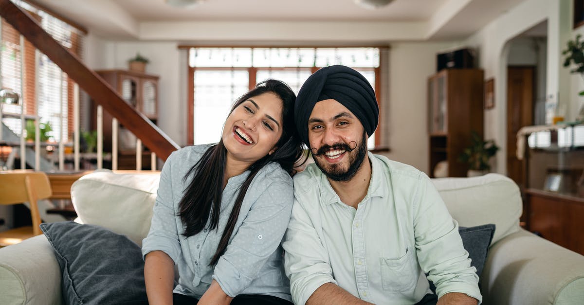 Will I have issues obtaining an Indian visa as a Pakistani-American? - Delighted young Indian couple relaxing and laughing together on couch at home Will I have issues obtaining an Indian visa as a Pakistani-American? - Delighted young Indian couple relaxing and laughing together on couch at home