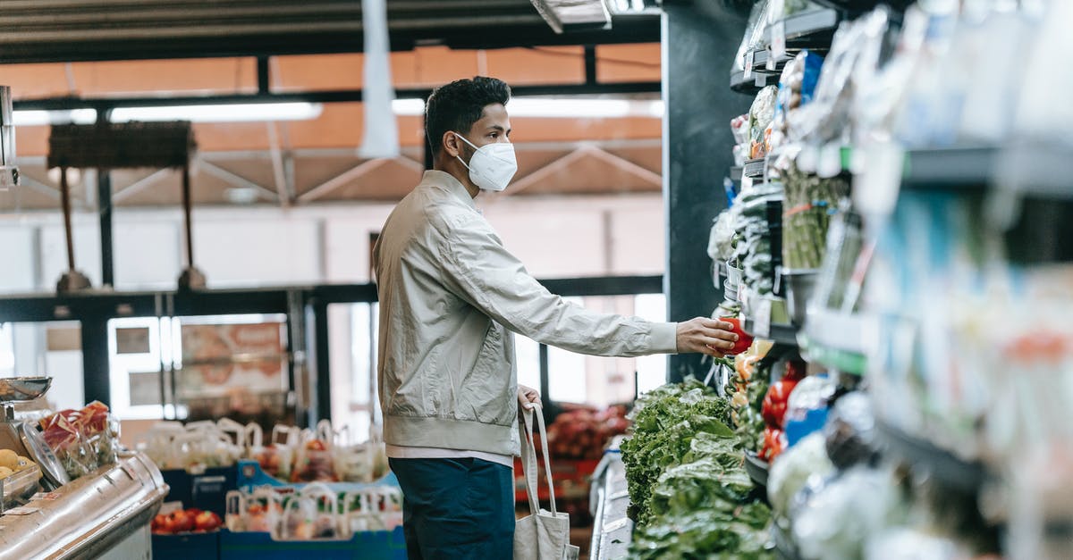 Will I have to clear Customs, pick up my bag and recheck it when flying BFS-EWR-YVR? [duplicate] - Man in mask choosing fresh groceries in store