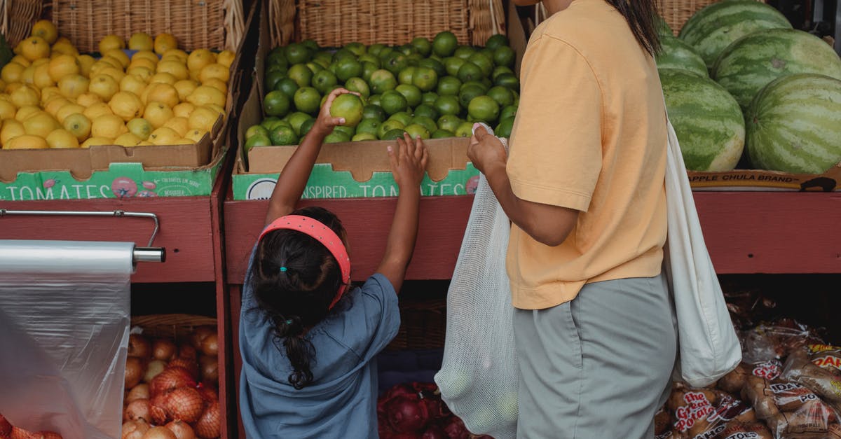 Will I have to clear Customs, pick up my bag and recheck it when flying BFS-EWR-YVR? [duplicate] - Ethnic girl choosing fruit from box in bazaar with mother