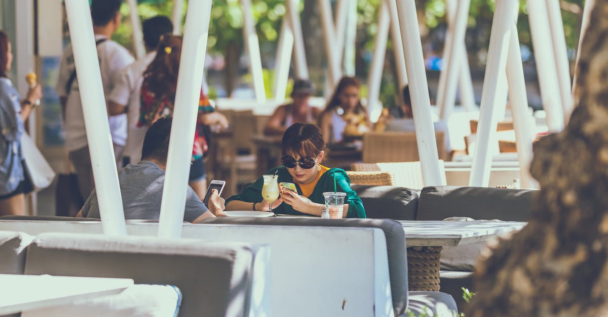 Will it be safe to travel to Bali in November 2018? [closed] - Woman Sitting on Chair Facing Man Holding Smartphone