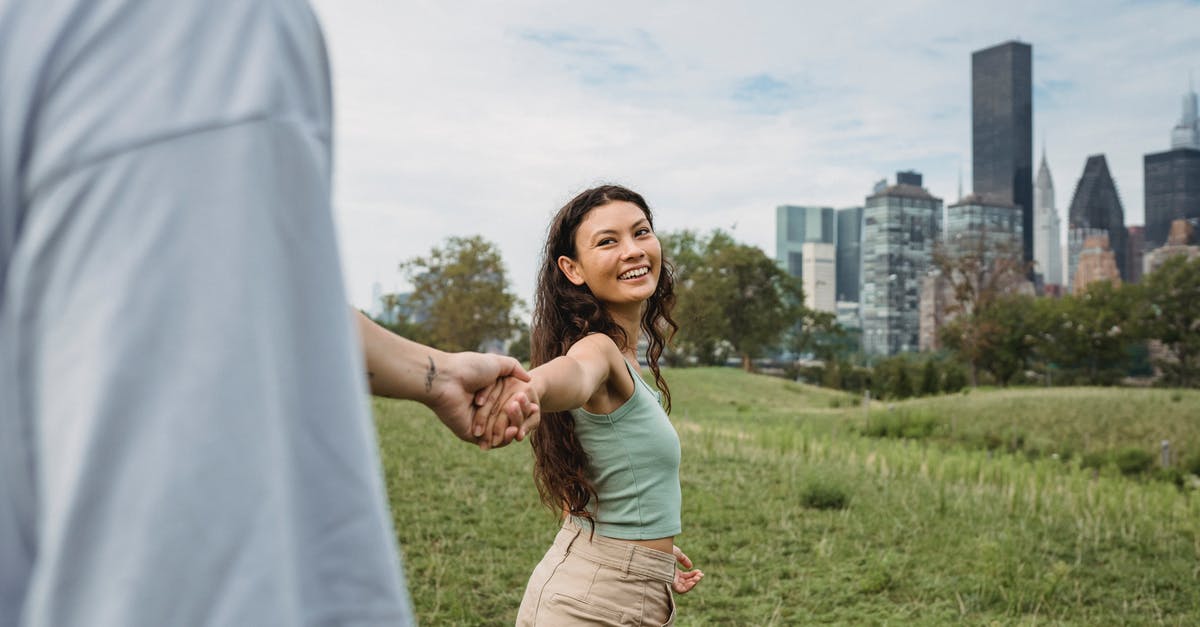 Will US boyfriend have issue visiting me in UK for 3 months? - Crop anonymous man holding hand and following happy young ethnic girlfriend while spending time together in green park in New York