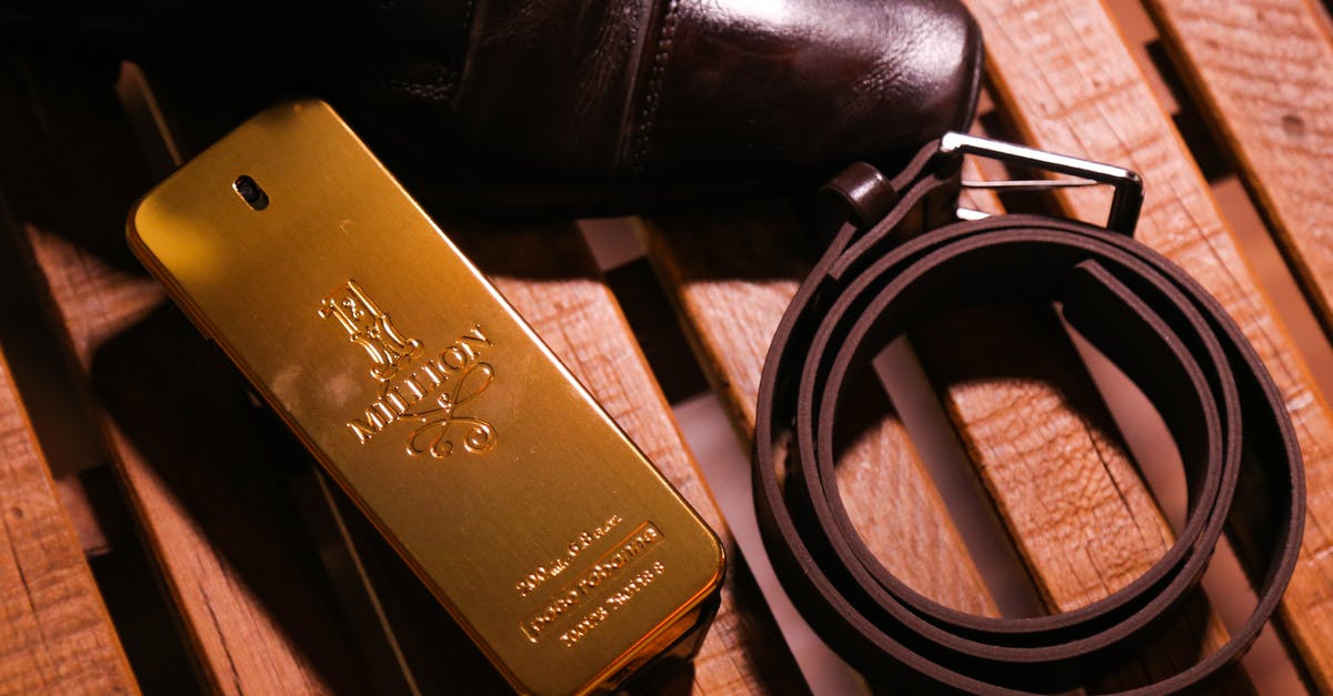 Within Dubai, is duty-free gold cheaper for comparable quality from the local Souk? [closed] - Elegant black luxury glossy man shoes and belt composing with perfume in bottle in form of gold bar on wooden bench