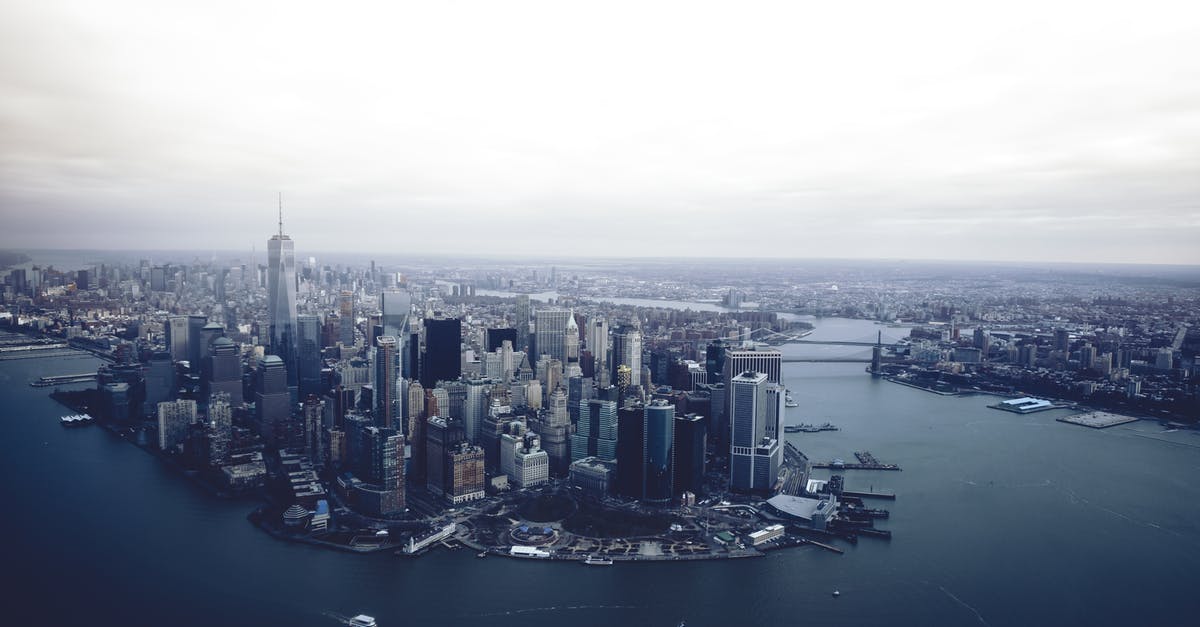 Work remotely for a US employer - Travel to US on tourist visa - Work remotely from hotel/friends part time - Modern city commercial district located on shore of river on cloudy day Work remotely for a US employer - Travel to US on tourist visa - Work remotely from hotel/friends part time - Modern city commercial district located on shore of river on cloudy day