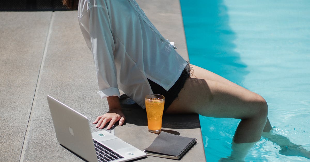 Working remotely on the French work and holiday visa? - From above side view of crop unrecognizable female traveler sitting on pool border with legs in water while relaxing after remote job on laptop Working remotely on the French work and holiday visa? - From above side view of crop unrecognizable female traveler sitting on pool border with legs in water while relaxing after remote job on laptop