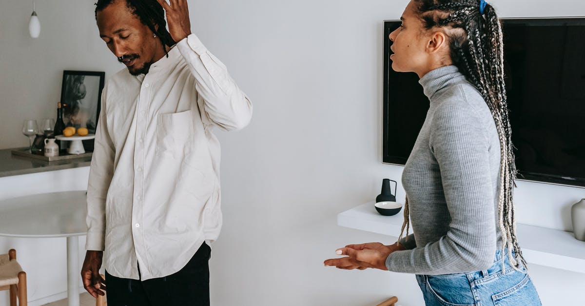 Worried that my parents information might not match - Tired young ethnic man with dreadlocks in casual outfit gesticulating while having argument with wife at home