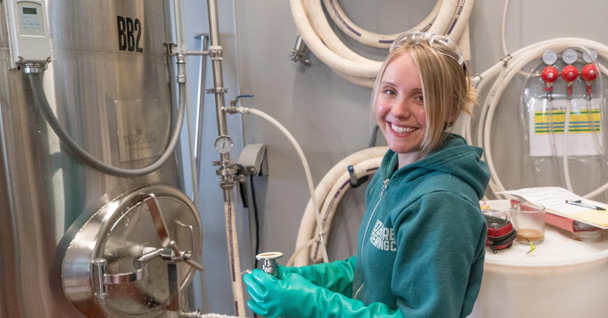 Would you have to remove your jacket for the X-ray machine if you're not wearing anything underneath? - Woman Wearing Pair of Teal Rubber Gloves Standing Near White Barrel Would you have to remove your jacket for the X-ray machine if you're not wearing anything underneath? - Woman Wearing Pair of Teal Rubber Gloves Standing Near White Barrel